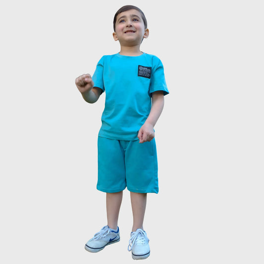 Smiling boy in blue t-shirt and shorts set with white sneakers, kids summer fashion