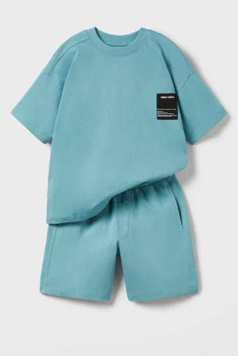 Sky blue kids fleece t-shirt and shorts set with chest logo patch, laid flat on white